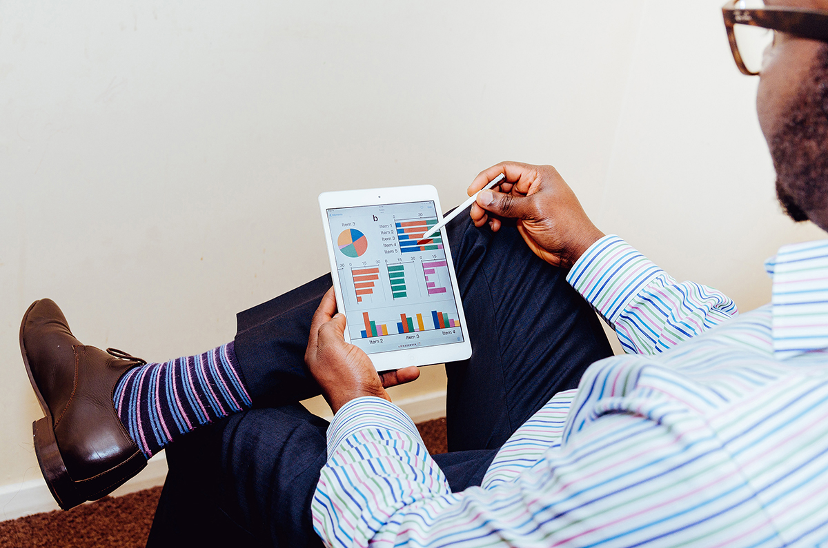 Close up of a man using an iPad to look at different graphs